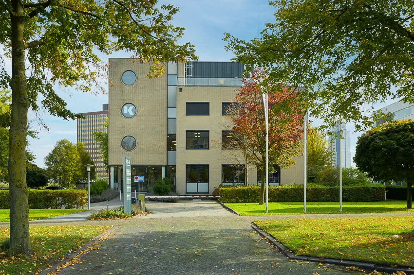Kantoorgebouw aan de K.P. van der Mandelelaan, omgeven door bomen en groen.